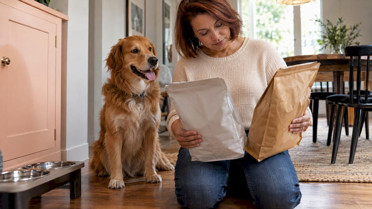 Woman choosing dog food beside her happy dog