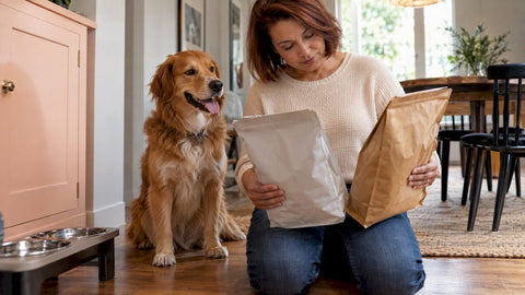 Woman choosing dog food beside her happy dog